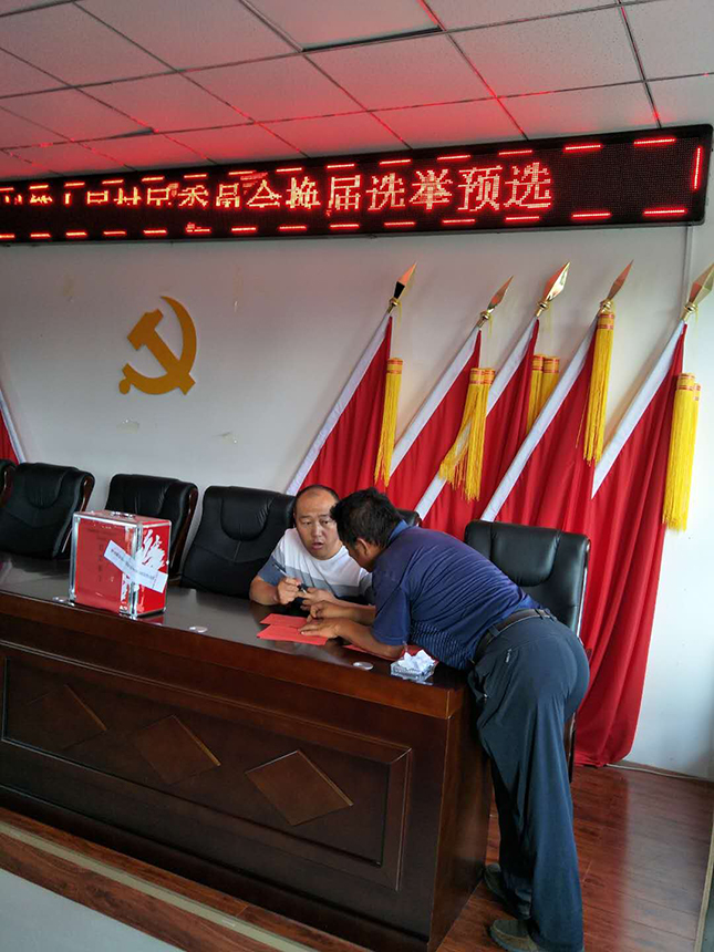 10 市侨联驻村第一书记巴雅尔在帮助村民填写选票.jpg